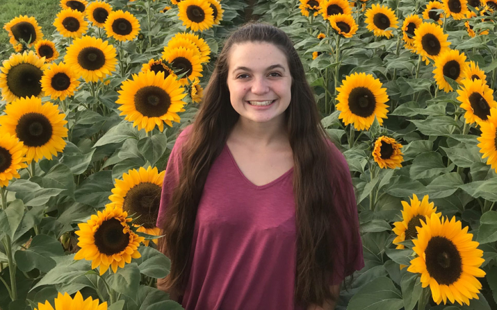 Headshot of Alex Welsh in a sunflower field 