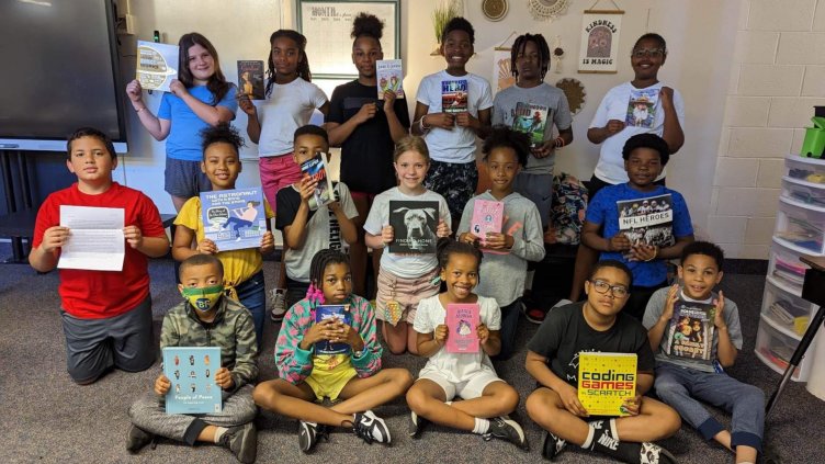 fourth grade students holding books