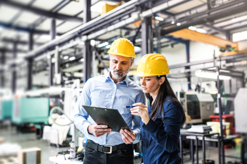 A portrait of an industrial man and woman engineers in a factory checking documents.