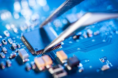 Close up of tweezers assembling a circuit board