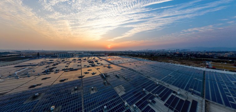 Aerial view of a solar power plant on the roof of a factory at sunset
