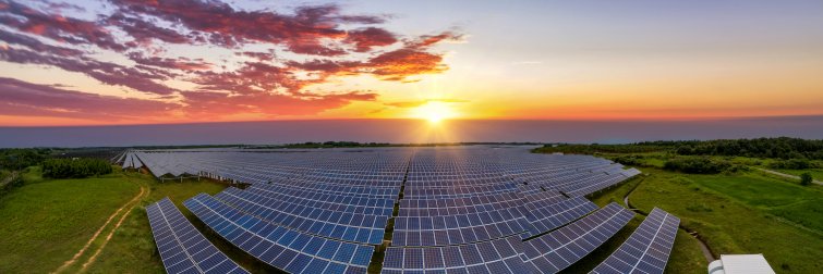 Panoramic aerial view of a sunset reflecting off of a solar farm