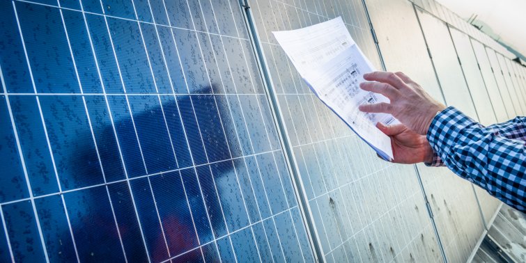 Man holding paper document against row of solar cells