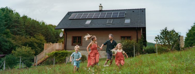 Happy family running near their house with solar panels