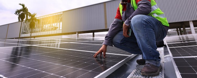 Close up of a engineer kneeling on solar panels on a rooftop