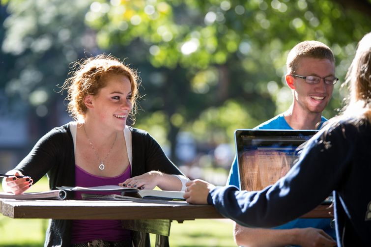 students on campus quad studying at picnic table